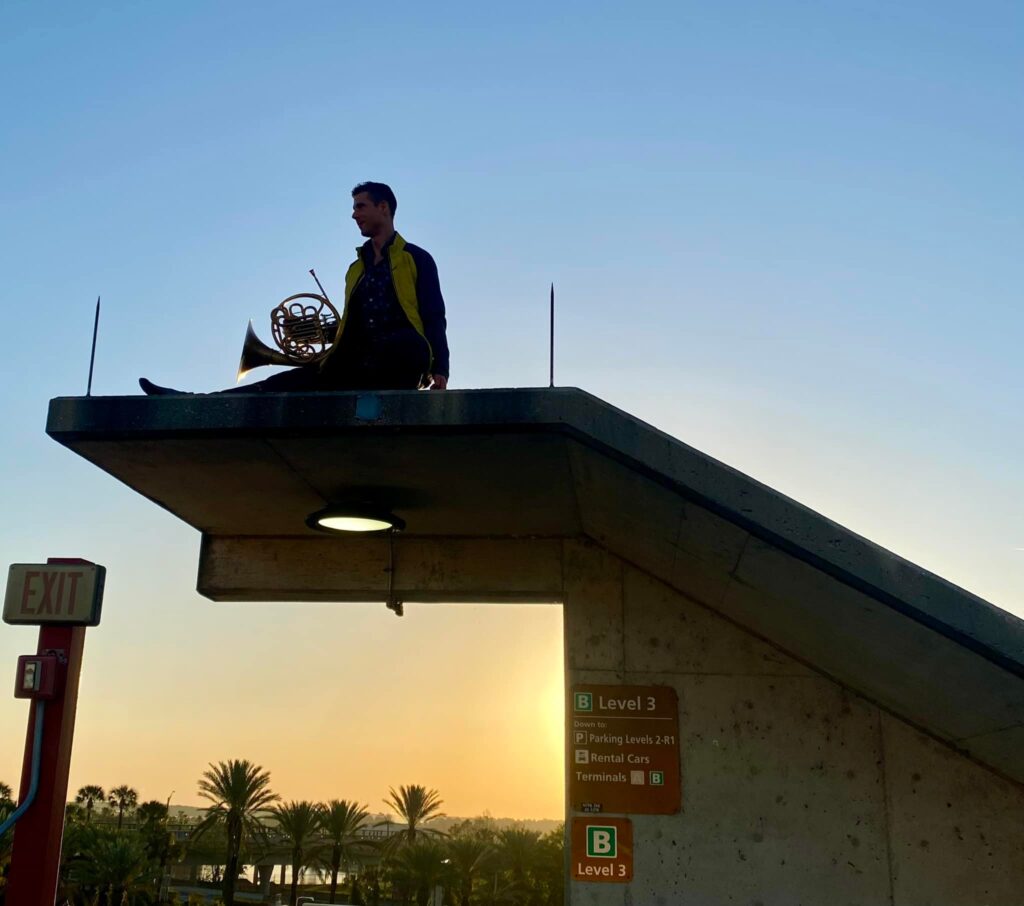 Mars Gelfo practicing french horn at Orlando International Airport sunrise